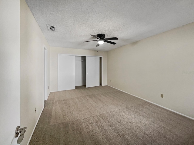 unfurnished bedroom featuring a closet, ceiling fan, carpet, and a textured ceiling