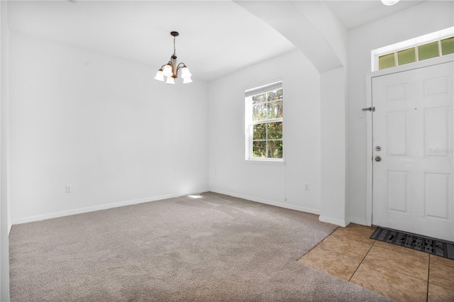 carpeted entryway with a notable chandelier, baseboards, and tile patterned floors