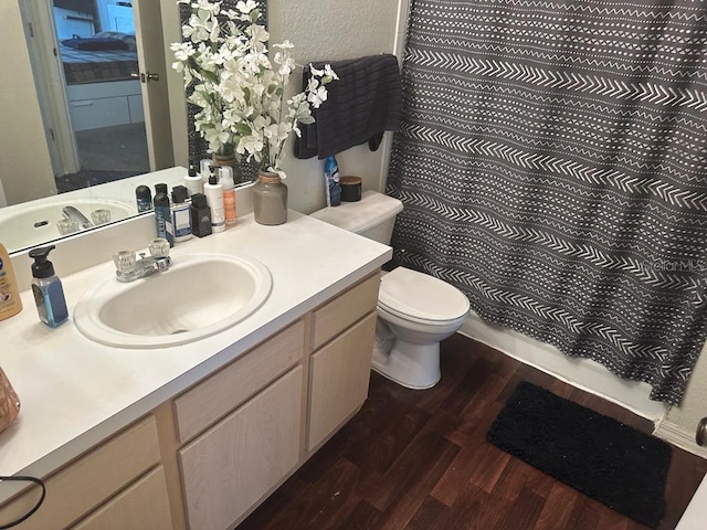 bathroom with vanity with extensive cabinet space, hardwood / wood-style flooring, and toilet