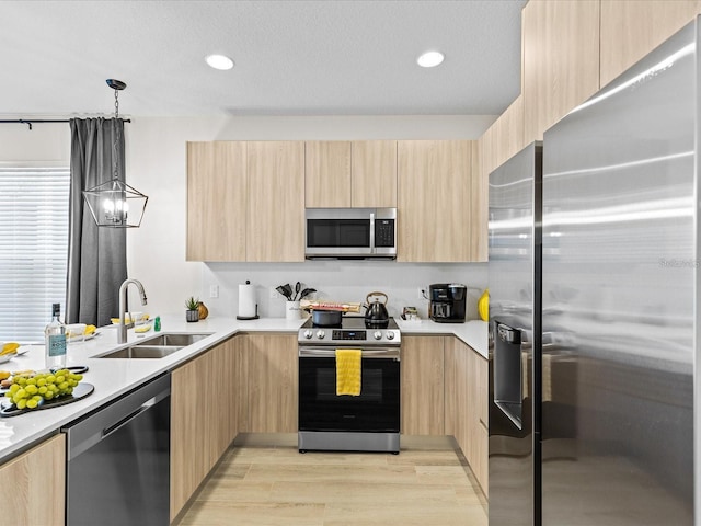 kitchen featuring pendant lighting, light hardwood / wood-style flooring, light brown cabinets, appliances with stainless steel finishes, and sink