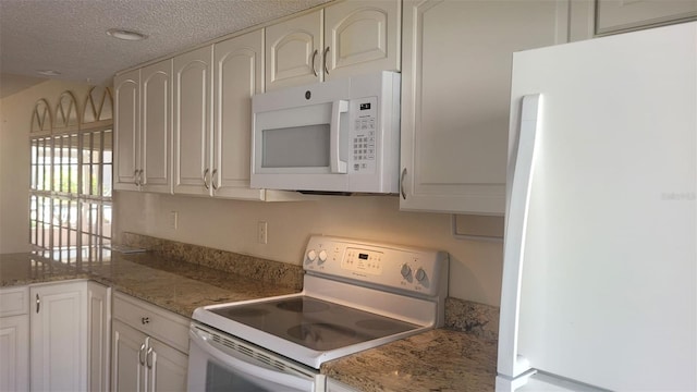 kitchen with white cabinets, white appliances, stone countertops, and a textured ceiling