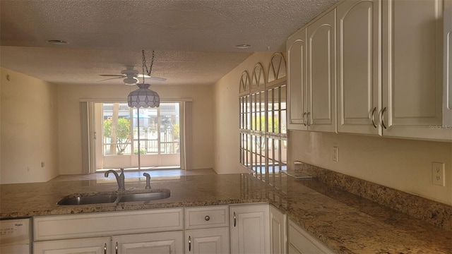 kitchen featuring white cabinets, sink, light stone countertops, and dishwashing machine