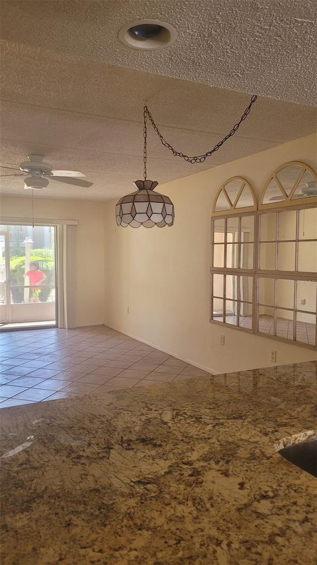 tiled spare room with ceiling fan and a textured ceiling