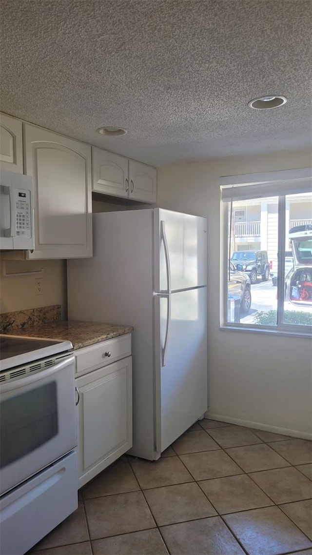 kitchen featuring white cabinets, white appliances, light tile flooring, and a textured ceiling