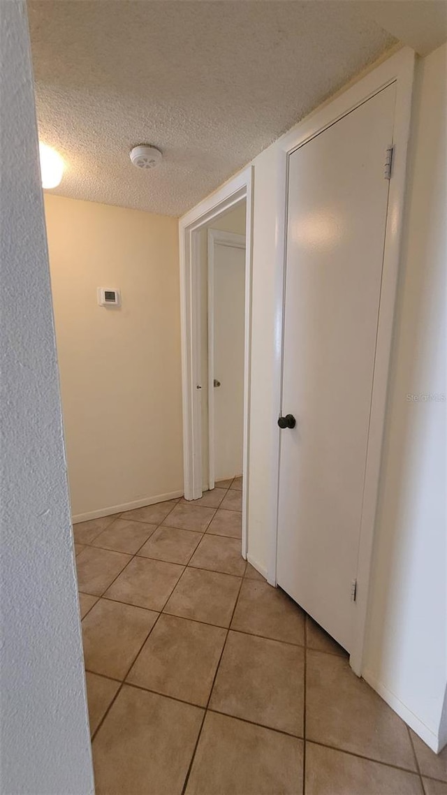 hallway featuring a textured ceiling and light tile flooring