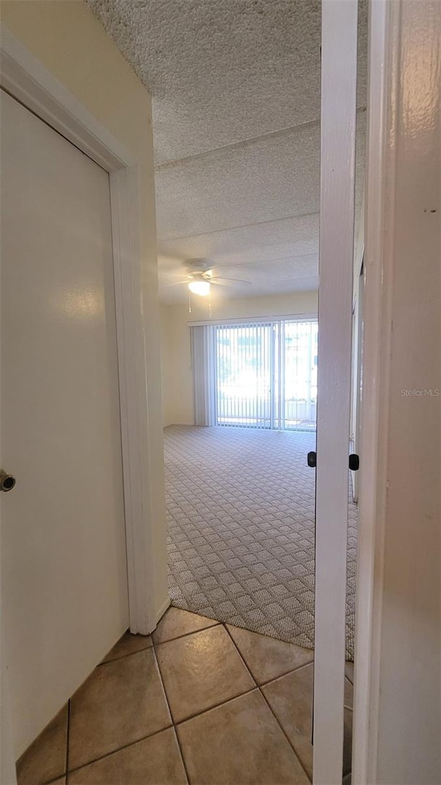 hall featuring tile floors and a textured ceiling