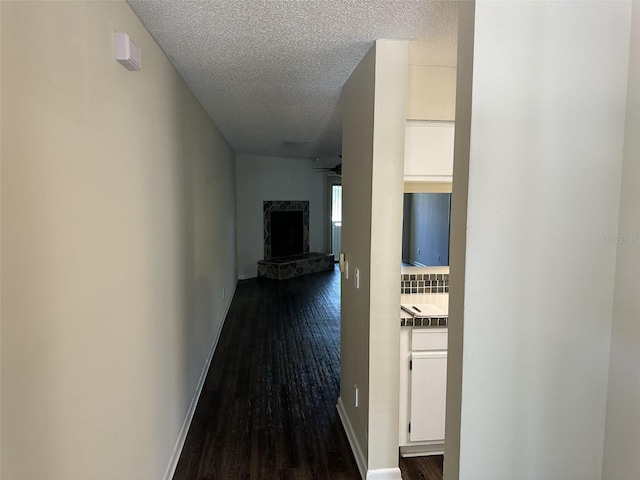 hall with a textured ceiling and dark wood-type flooring