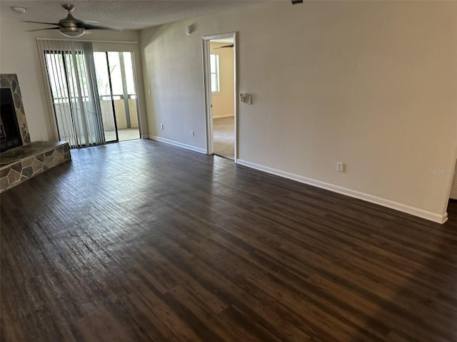 unfurnished living room with dark hardwood / wood-style floors, a fireplace, and ceiling fan