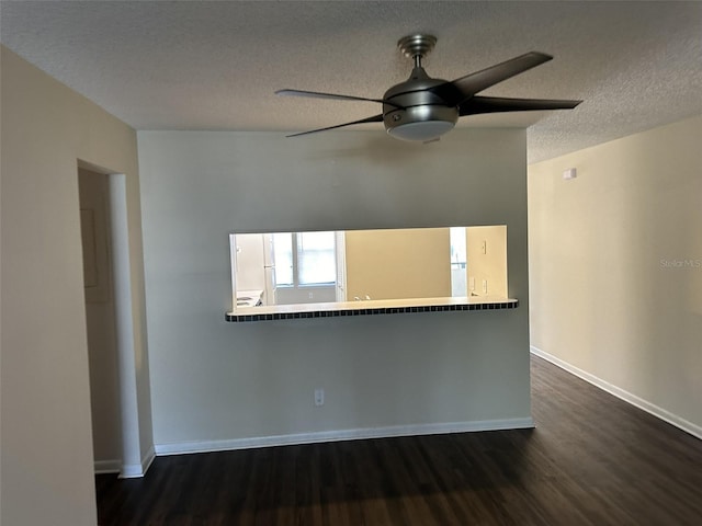 spare room with a textured ceiling, ceiling fan, and dark wood-type flooring