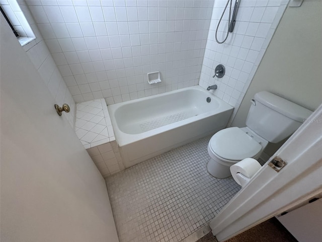 bathroom featuring tiled shower / bath, toilet, and tile floors