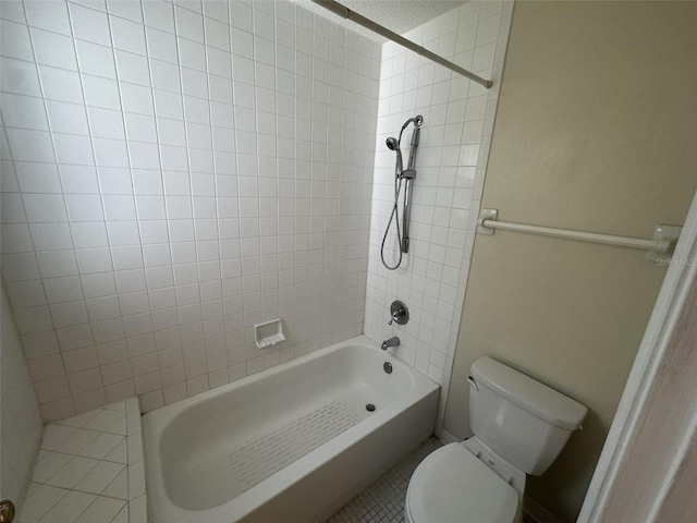 bathroom with tiled shower / bath combo, toilet, and tile flooring