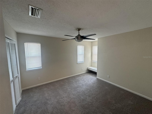 carpeted empty room with ceiling fan and a textured ceiling