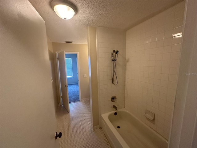 bathroom featuring tile flooring, tiled shower / bath, and a textured ceiling