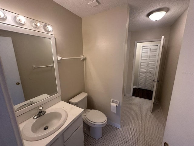 bathroom with vanity with extensive cabinet space, toilet, tile floors, and a textured ceiling