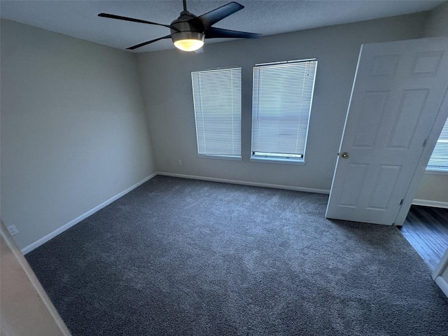 unfurnished bedroom featuring ceiling fan, multiple windows, and dark colored carpet