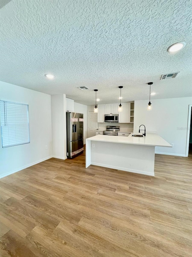 kitchen featuring pendant lighting, white cabinets, light wood-type flooring, appliances with stainless steel finishes, and sink