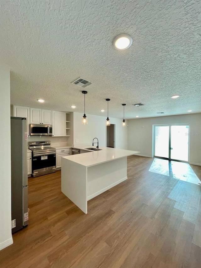 kitchen featuring sink, stainless steel appliances, a textured ceiling, white cabinets, and hardwood / wood-style floors