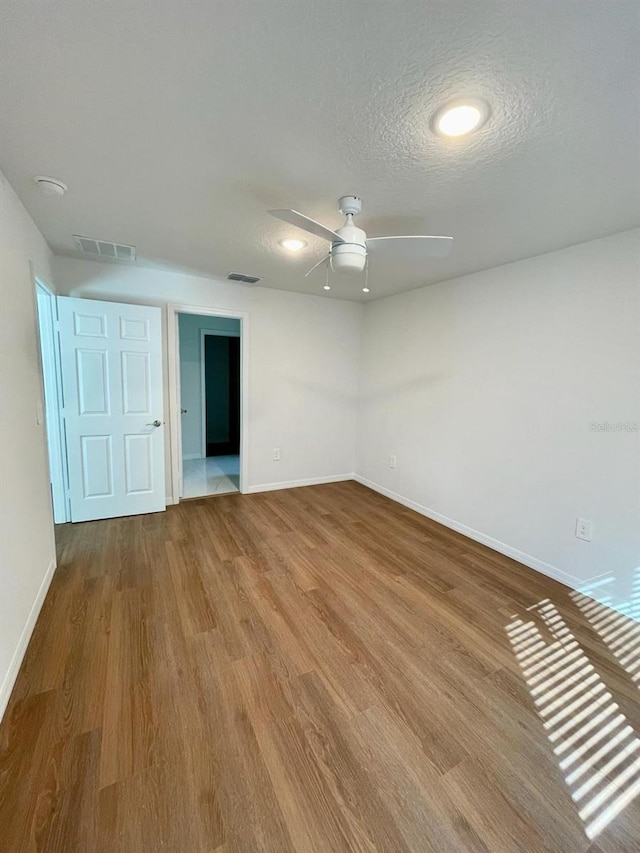 empty room with wood-type flooring, ceiling fan, and a textured ceiling