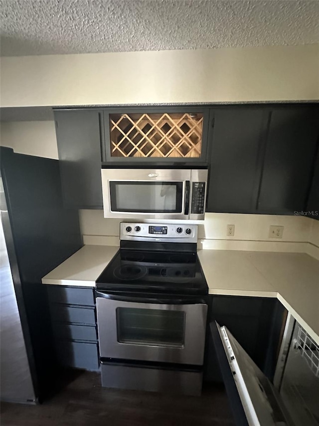 kitchen with appliances with stainless steel finishes, dark wood-type flooring, and a textured ceiling