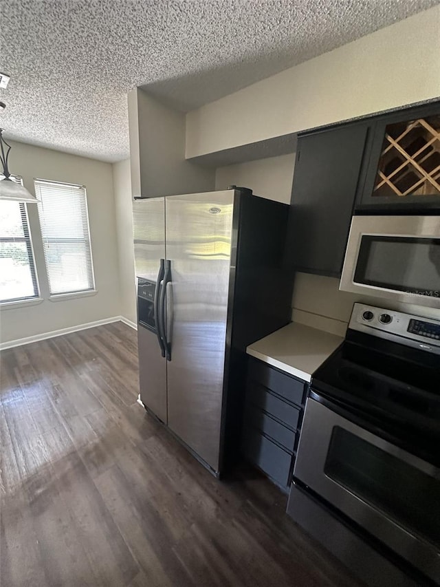 kitchen with appliances with stainless steel finishes, dark hardwood / wood-style flooring, and a textured ceiling