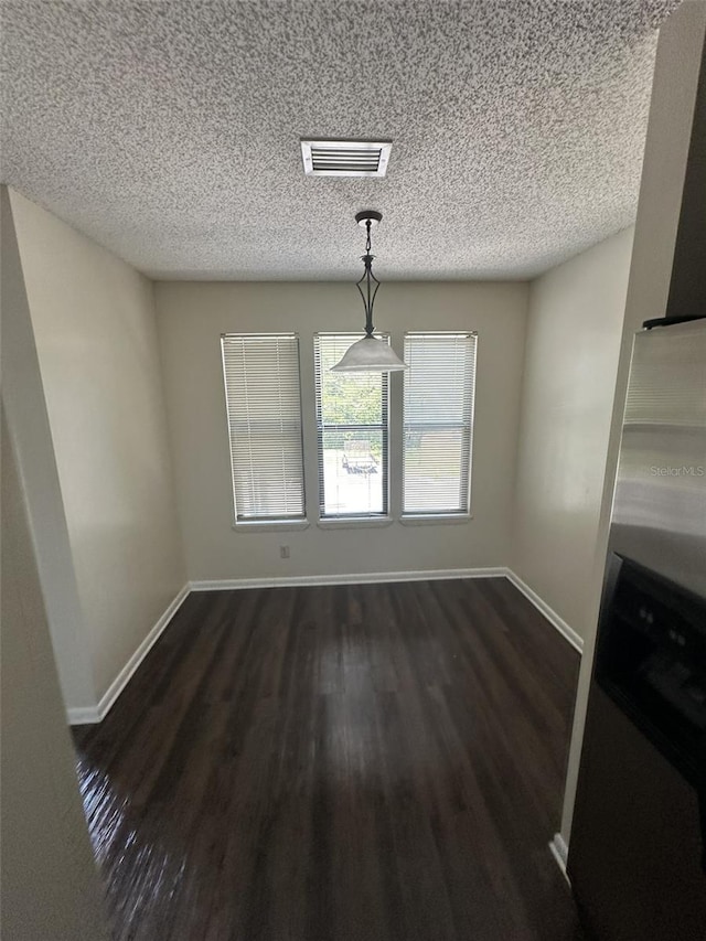 unfurnished dining area with dark hardwood / wood-style flooring and a textured ceiling