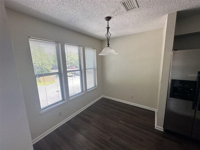 unfurnished dining area with a textured ceiling and dark wood-type flooring