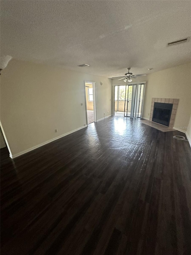 unfurnished living room with ceiling fan, a fireplace, dark hardwood / wood-style floors, and a textured ceiling