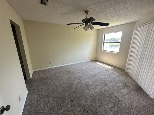 carpeted empty room with ceiling fan and a textured ceiling