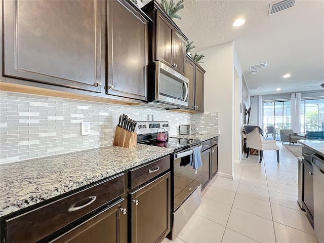 kitchen with light stone countertops, stainless steel appliances, light tile floors, tasteful backsplash, and dark brown cabinetry