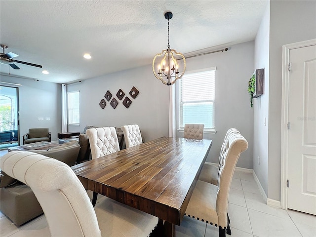 dining area featuring ceiling fan with notable chandelier, a textured ceiling, a wealth of natural light, and light tile floors