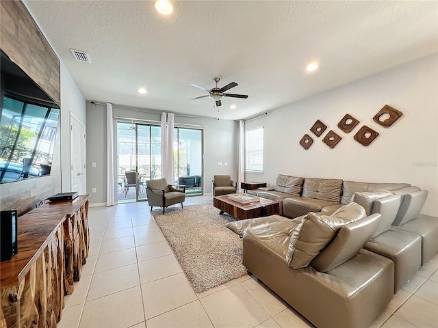 tiled living room featuring a healthy amount of sunlight, a textured ceiling, and ceiling fan