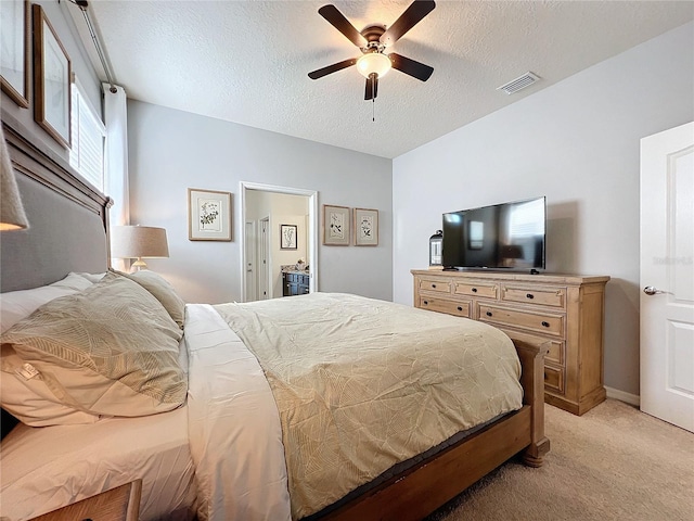 carpeted bedroom featuring ensuite bath, ceiling fan, and a textured ceiling