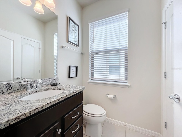 bathroom with a wealth of natural light, oversized vanity, toilet, and tile flooring