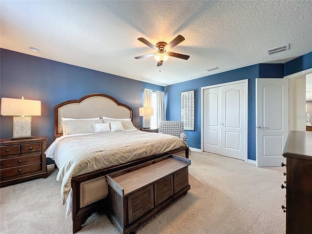 carpeted bedroom with a closet, a textured ceiling, and ceiling fan