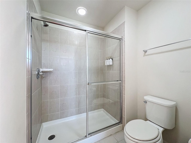 bathroom with a shower with door, tile floors, and toilet