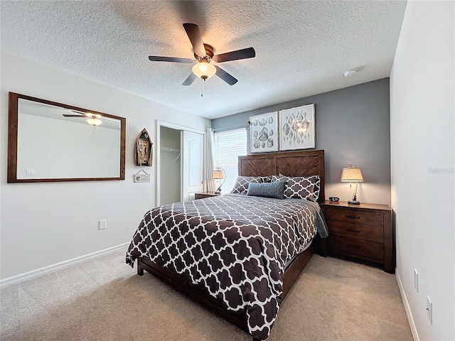 carpeted bedroom with a closet, a textured ceiling, and ceiling fan