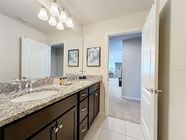 bathroom with a textured ceiling, dual sinks, oversized vanity, tile floors, and an inviting chandelier