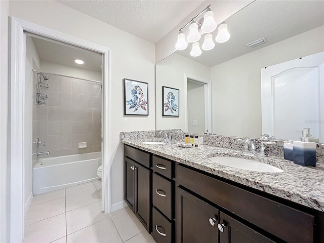 full bathroom with tiled shower / bath combo, a textured ceiling, tile floors, toilet, and dual bowl vanity