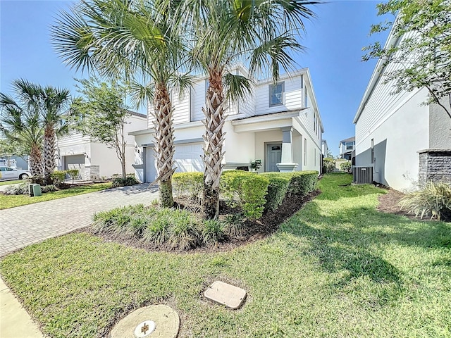 view of front of property featuring central AC unit, a front lawn, and a garage