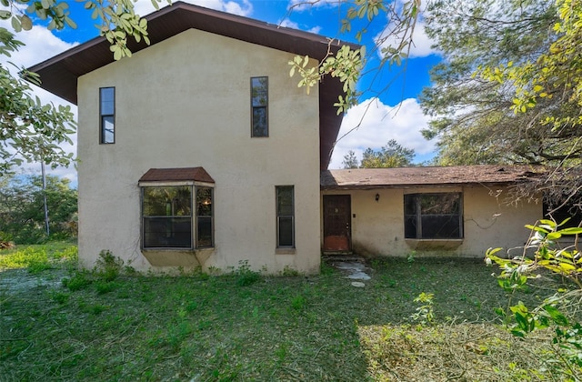 rear view of property with a yard and stucco siding