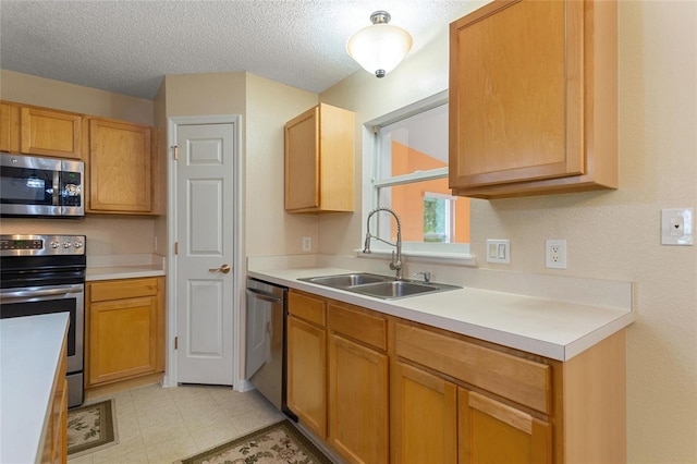 kitchen featuring a textured ceiling, sink, stainless steel appliances, and light tile flooring