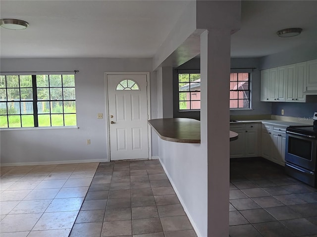 interior space with white cabinets, dark tile floors, and electric stove