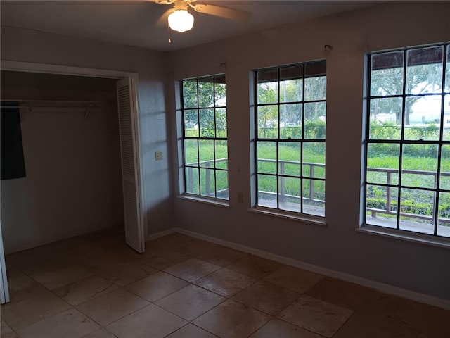 unfurnished bedroom featuring a closet, ceiling fan, multiple windows, and tile flooring