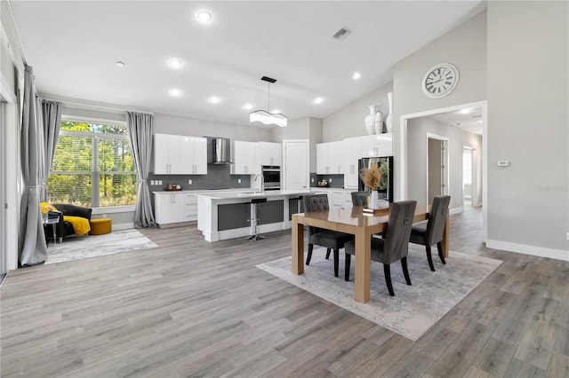 dining space with high vaulted ceiling, light hardwood / wood-style floors, and sink