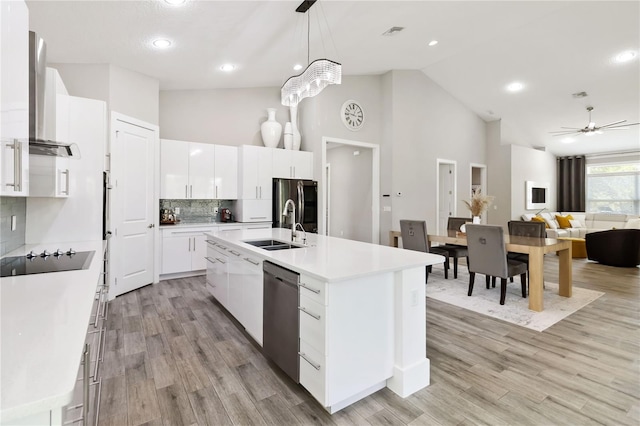 kitchen with ceiling fan, appliances with stainless steel finishes, light hardwood / wood-style flooring, white cabinetry, and a center island with sink