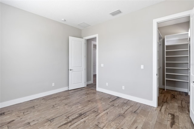 unfurnished bedroom featuring wood-type flooring and a spacious closet