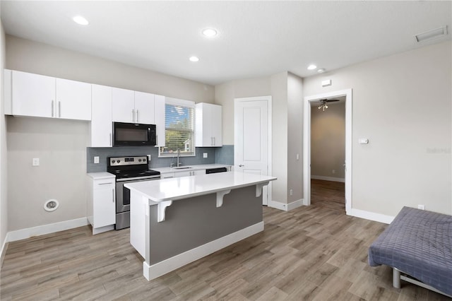 kitchen with stainless steel electric range oven, a center island, backsplash, and white cabinets