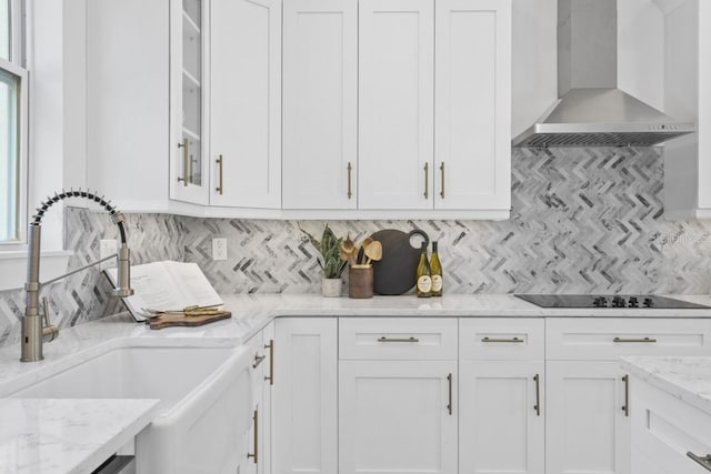 kitchen with white cabinets, wall chimney range hood, sink, and tasteful backsplash