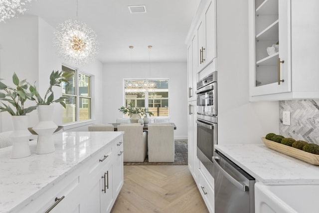 kitchen featuring appliances with stainless steel finishes, a notable chandelier, light parquet floors, and a healthy amount of sunlight