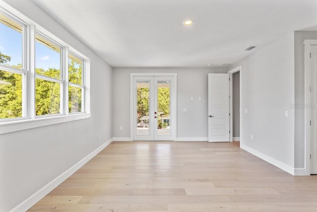 empty room featuring french doors and light wood-type flooring